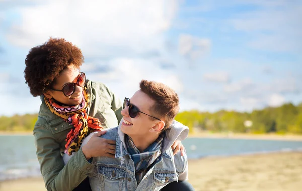 Happy teenage couple in shades having fun on beach — Stock Photo, Image