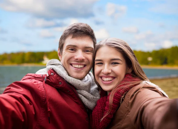 Gelukkige jonge paar nemen selfie op herfst strand — Stockfoto