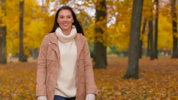 Glückliche junge Frau geht im Herbstpark spazieren — Stockvideo