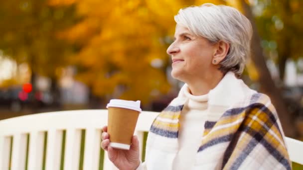 Senior kvinna dricker kaffe i höstparken — Stockvideo