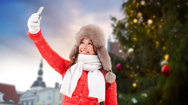 Woman taking selfie over christmas tree — Stock Photo, Image