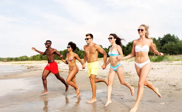 Amigos felizes correndo na praia de verão — Fotografia de Stock