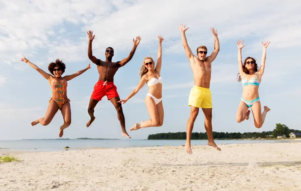 Happy přátelé skákání na letní beach — Stock fotografie