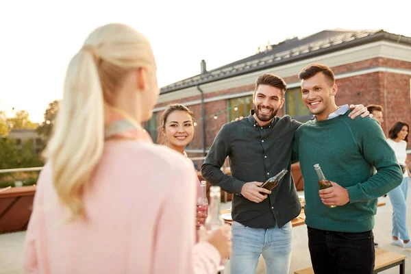 Amici felici con bevande che si abbracciano alla festa sul tetto — Foto Stock