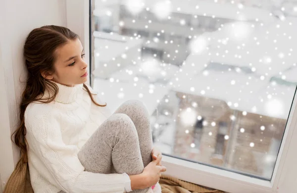 겨울에 창 문 턱에서 집에 앉아 슬픈 소녀 — 스톡 사진