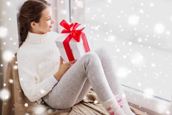 Mädchen mit Weihnachtsgeschenk sitzt auf Fensterbank — Stockfoto