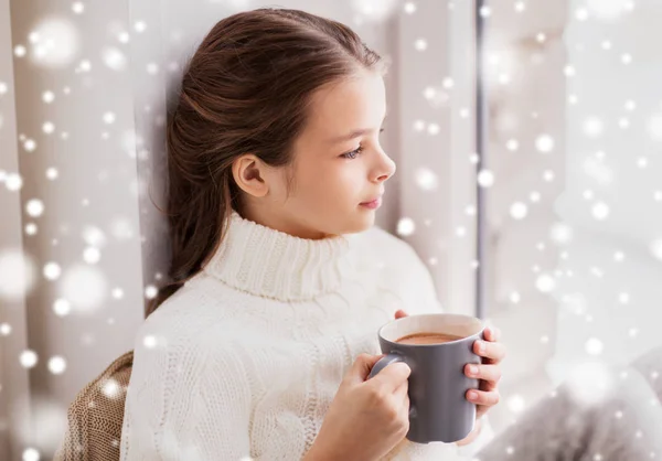 Meisje in winter trui met cacao mok ter venster — Stockfoto