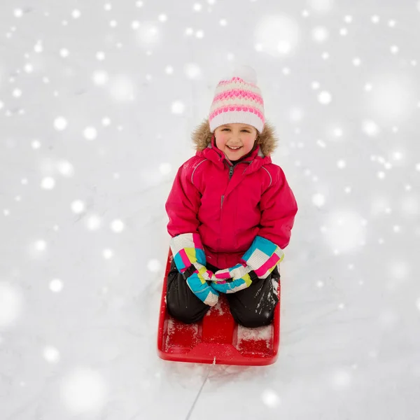Gelukkig meisje slee rijden op sneeuw in de winter — Stockfoto