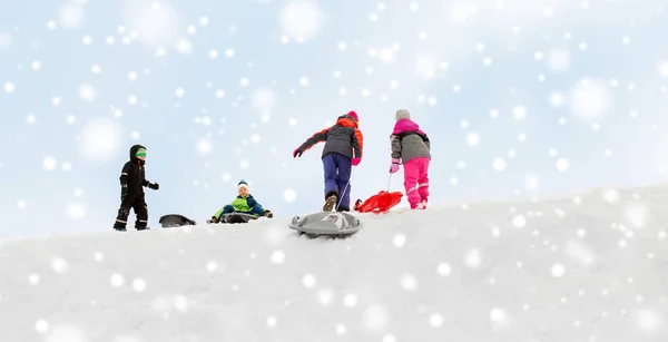 Crianças com trenós escalando neve colina no inverno — Fotografia de Stock