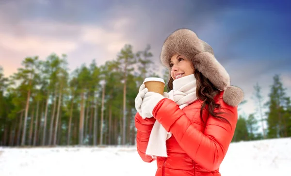 Mulher em chapéu de pele com café sobre floresta de inverno — Fotografia de Stock