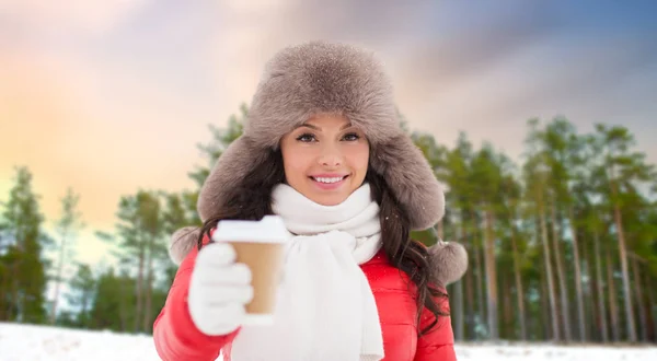 Женщина в меховой шляпе с кофе над зимним лесом — стоковое фото