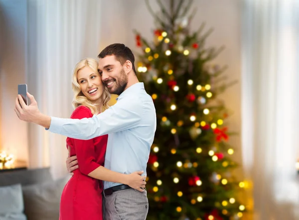 Пара делает селфи на смартфоне на Рождество — стоковое фото