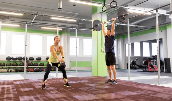 Hombre y mujer con pesas haciendo ejercicio en el gimnasio — Foto de Stock