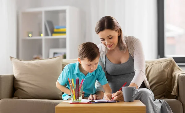 Mãe grávida e filho com caderno de trabalho em casa — Fotografia de Stock