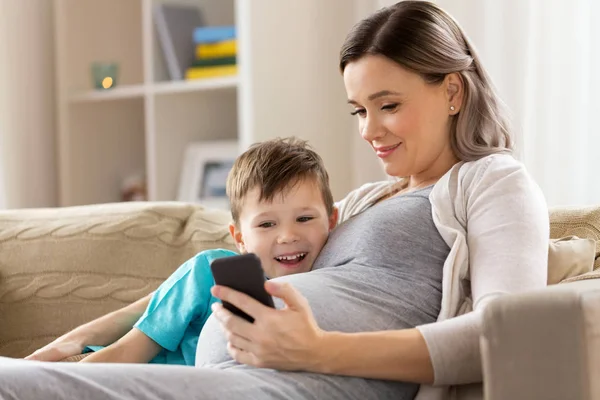 Mãe grávida e filho com smartphone em casa — Fotografia de Stock