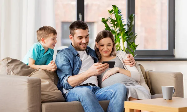 Famille heureuse avec smartphone à la maison — Photo