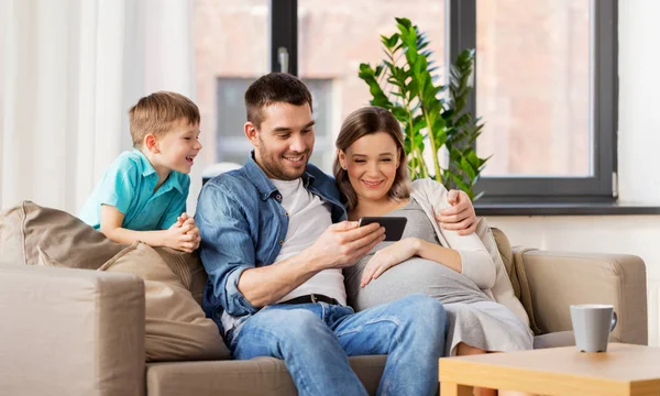 Glückliche Familie mit Smartphone zu Hause — Stockfoto