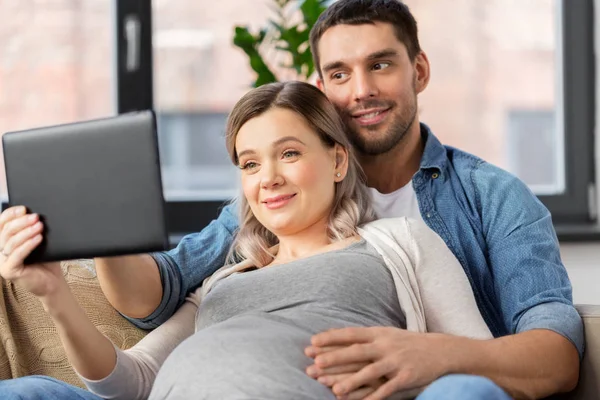 Mężczyzna i kobieta w ciąży z komputera typu tablet w domu — Zdjęcie stockowe