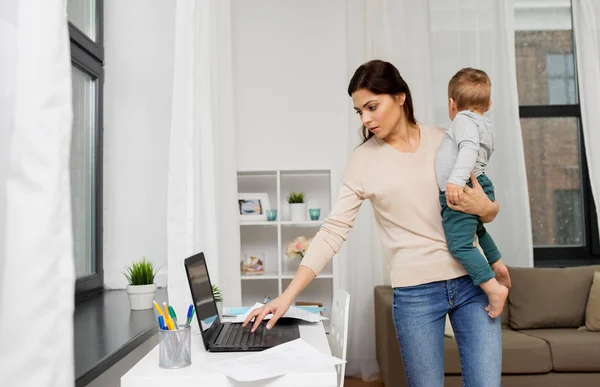 Madre con el bebé y el ordenador portátil trabajando en casa — Foto de Stock