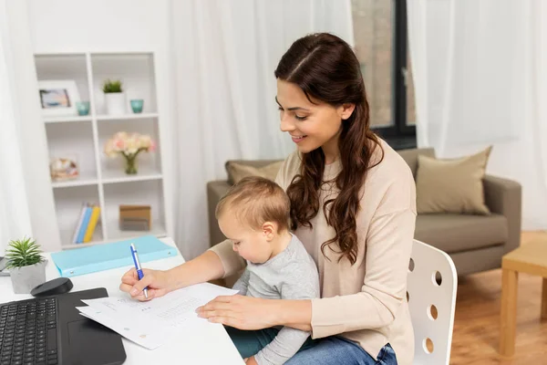 Boldog anya baba és papírok otthoni munkavégzés — Stock Fotó