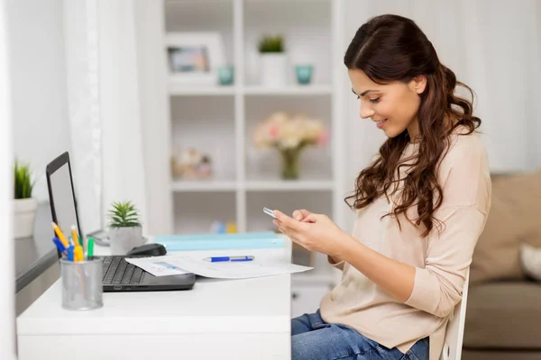 Femme avec papiers et smartphone travaillant à la maison — Photo