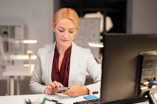 Mujer de negocios con teléfono inteligente en la oficina de noche — Foto de Stock