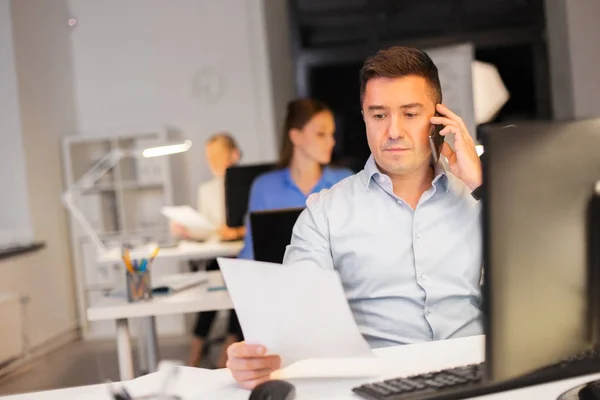 Homem chamando no smartphone no escritório da noite — Fotografia de Stock