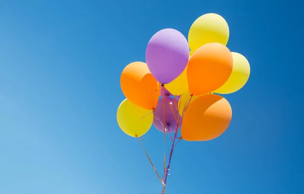 Primer plano de globos de helio de colores en el cielo azul — Foto de Stock