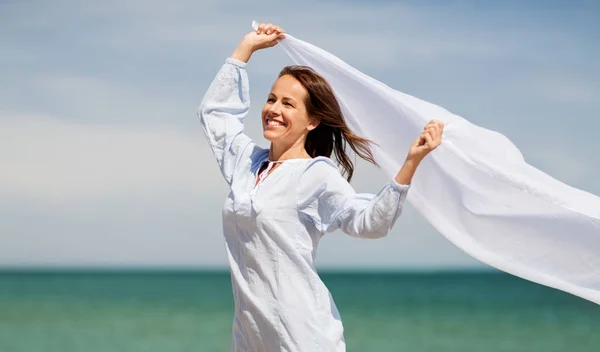 Mujer feliz con chal ondeando en el viento en la playa —  Fotos de Stock