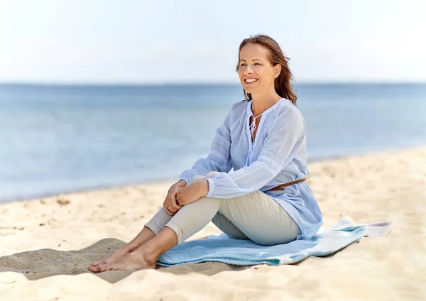 Ευτυχισμένη γυναίκα κάθεται στην παραλία το καλοκαίρι — Φωτογραφία Αρχείου