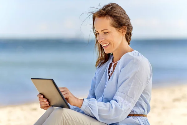 Glücklich lächelnde Frau mit Tablet-PC am Sommerstrand — Stockfoto