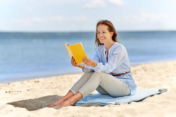 Szczęśliwy uśmiechający się kobieta, czytanie książki na lato Plaża — Zdjęcie stockowe