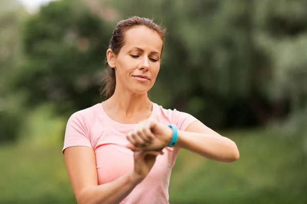 Frau mit Fitness-Tracker im Sommerpark — Stockfoto