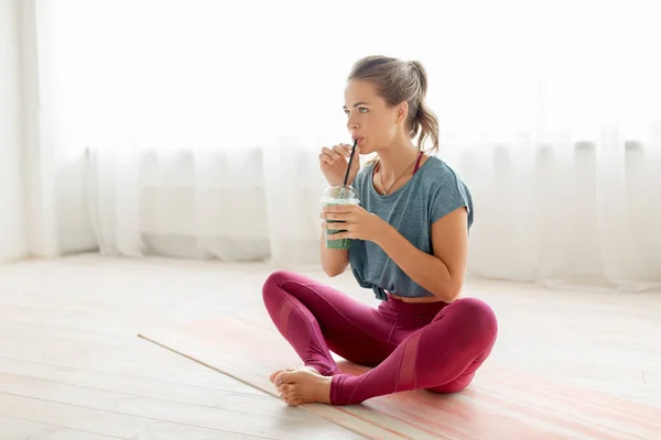 Женщина пьет из чашки смузи в студии йоги — стоковое фото