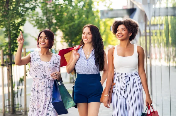 Gelukkig vrouwen met boodschappentassen wandelen in de stad — Stockfoto