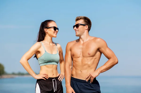 Felice coppia in abiti sportivi e ombre sulla spiaggia — Foto Stock