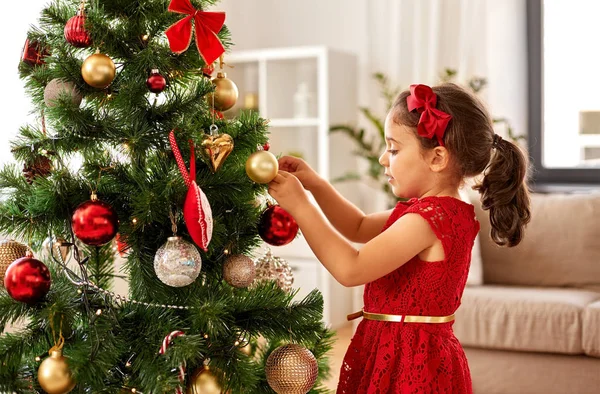 Kleines Mädchen schmückt Weihnachtsbaum zu Hause — Stockfoto