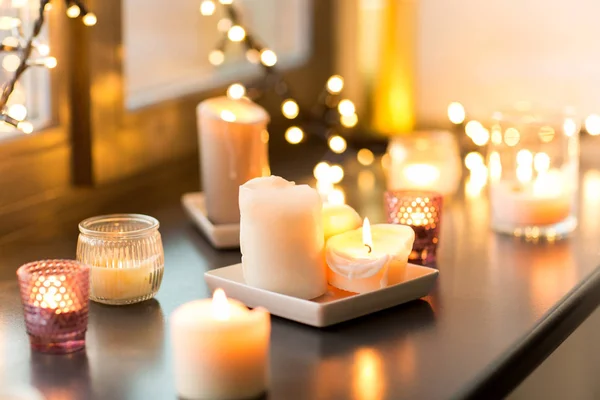 Candles burning on window sill with garland lights — Stock Photo, Image