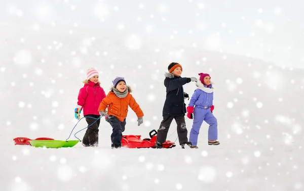 Glückliche kleine Kinder mit Schlitten im Winter — Stockfoto