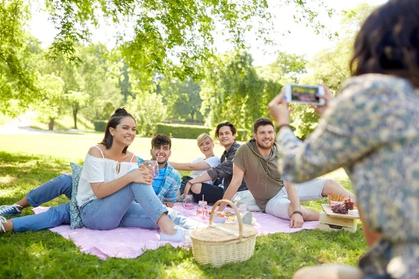 Vrienden fotograferen door smartphone op picnic — Stockfoto