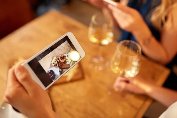 技术和生活方式概念 妇女的手通过智能手机描绘食物和在酒吧或餐馆喝酒 — 图库照片