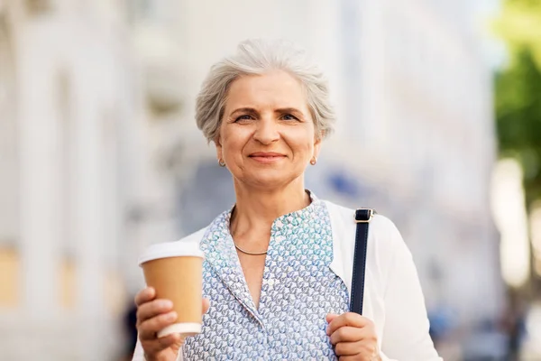 Пожилая женщина пьет кофе в летнем городе — стоковое фото