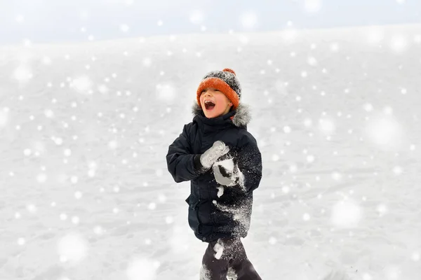 Glücklicher kleiner Junge, der im Winter mit Schnee spielt — Stockfoto