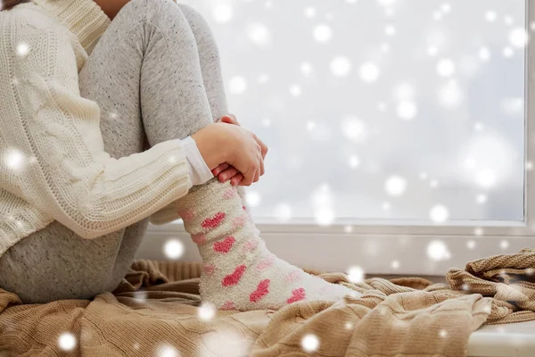 Fille assise sur le seuil à la fenêtre de la maison en hiver — Photo