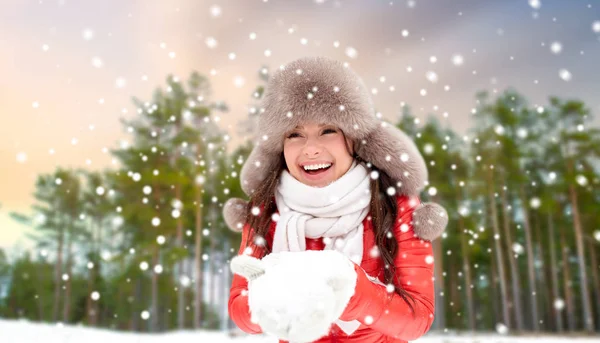 季节和休闲的概念 幸福的妇女在毛皮帽子雪在她的手在冬季森林背景 — 图库照片
