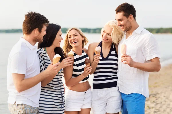 Amigos felices comiendo helado en la playa — Foto de Stock