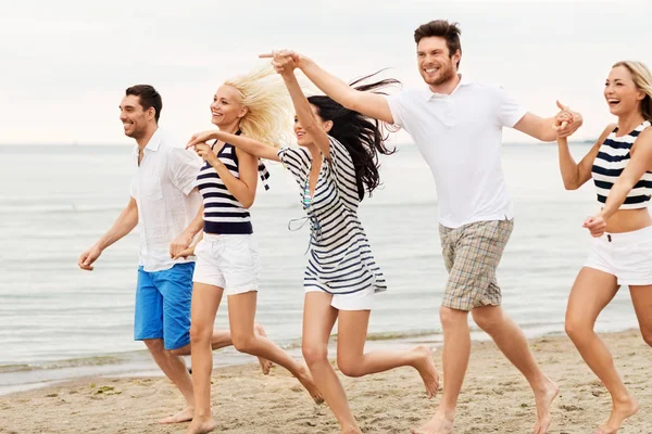 Friends in striped clothes running along beach — Stock Photo, Image