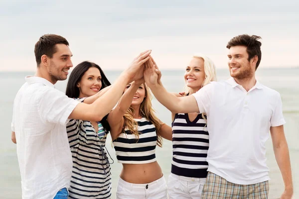 Glada vänner att göra high five på stranden — Stockfoto