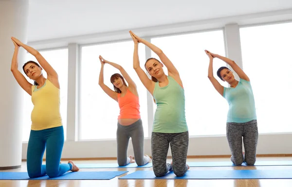 Mujeres embarazadas felices haciendo ejercicio sobre alfombras en el gimnasio — Foto de Stock