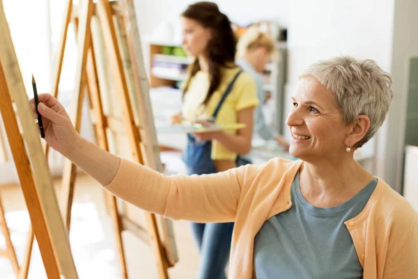 Senior femme dessin sur chevalet à l'école d'art studio — Photo